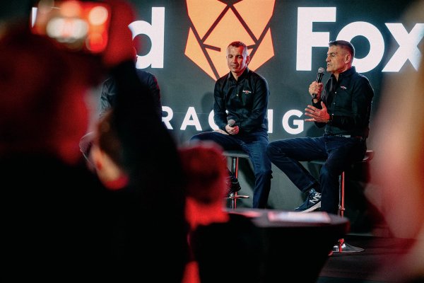Two Red Fox Racing team members speaking on stage with the crowd watching
