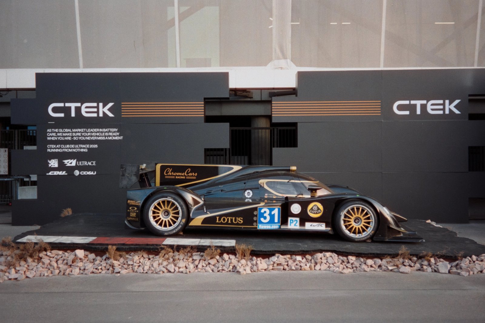 Chrome Cars Lotus LMP race car number 31 in black and gold livery in front of CTEK exhibitor stand