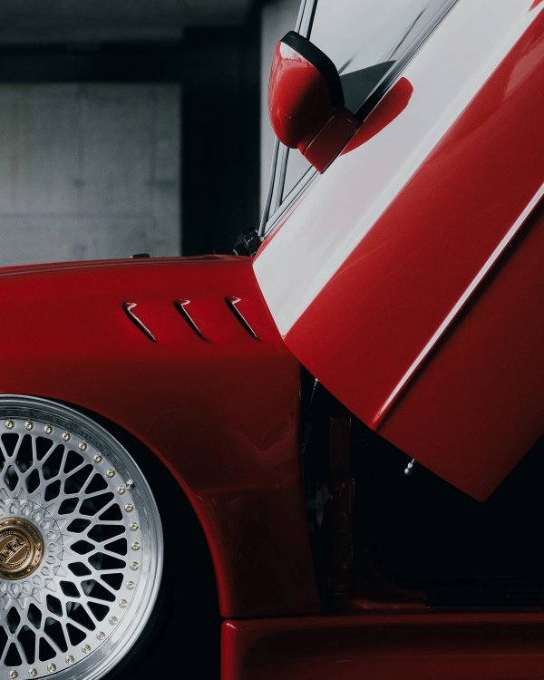 Red VW Corrado detail showing fender vent, wheel and red mirror