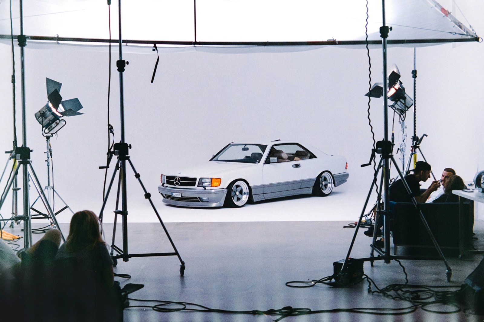 White Mercedes SEC AMG alone on set with a large butterfly overhead and tripods around