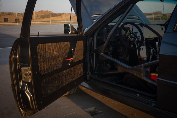 Open driver door revealing aramid door card, roll cage, and ECU Master controls inside the cockpit