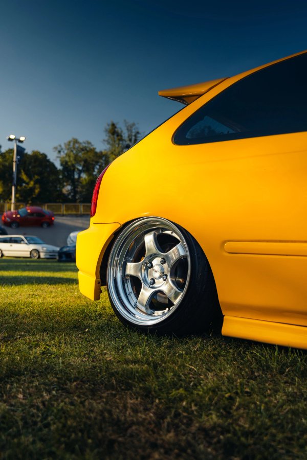 Yellow Honda Civic EK rear quarter on the grass at low angle with wheel tucked