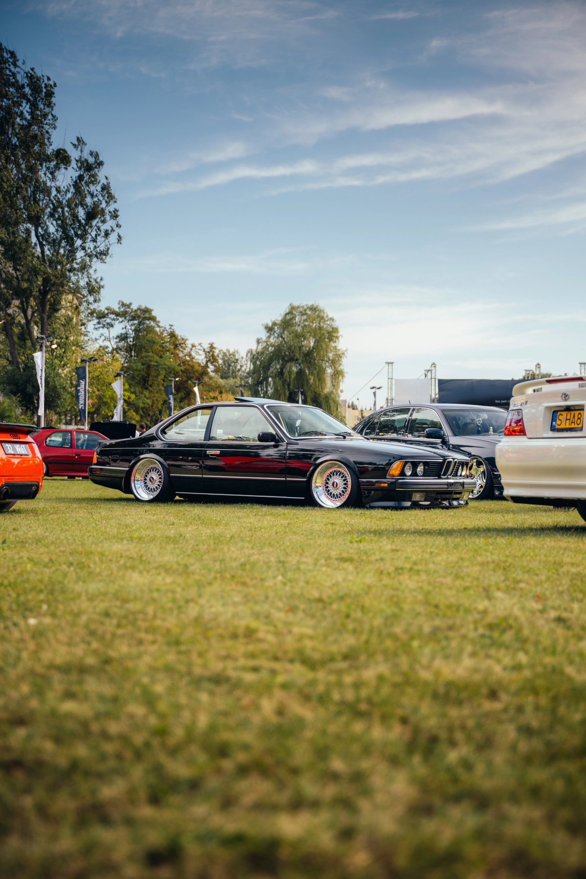 Black BMW E24 6-series on BBS wheels sitting low on the grass infield