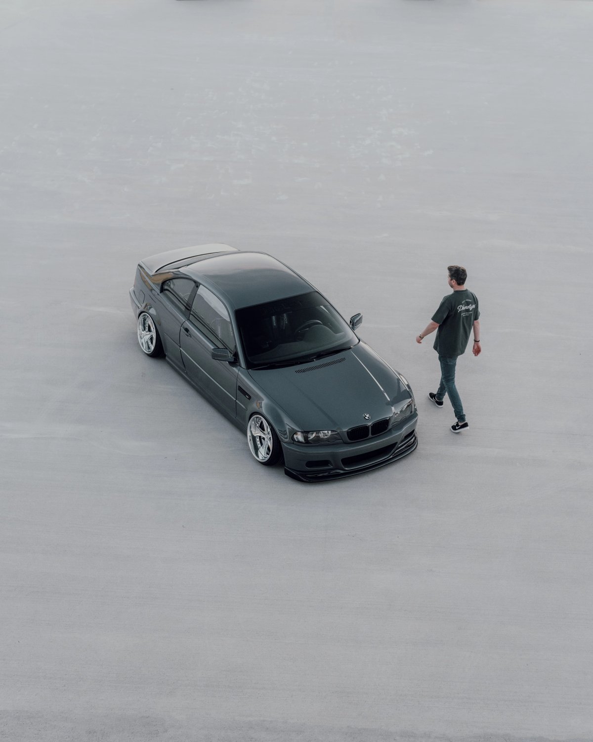 BMW E46 seen from above on empty concrete with a person walking away