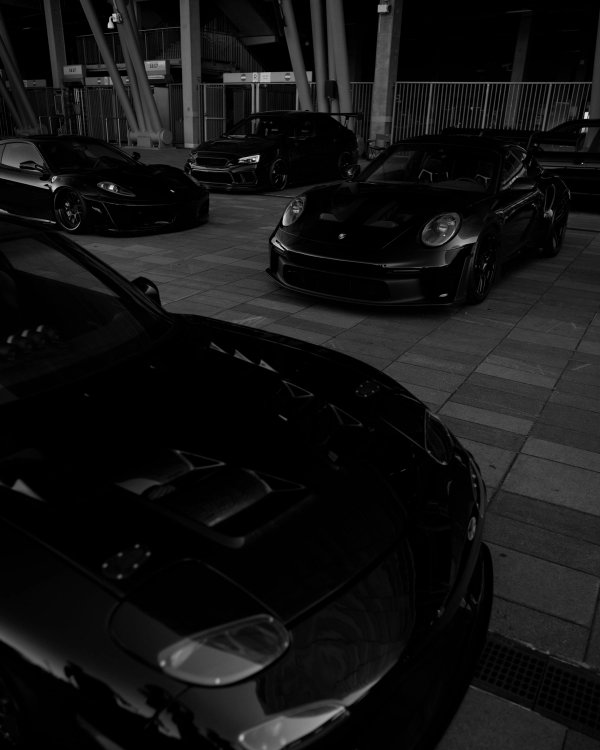 Black-on-black lineup of supercars and tuner cars in a moody covered space