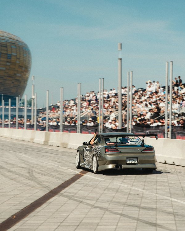 Japanese-plated Nissan Silvia S15 drift car with the driver waving to the packed grandstand
