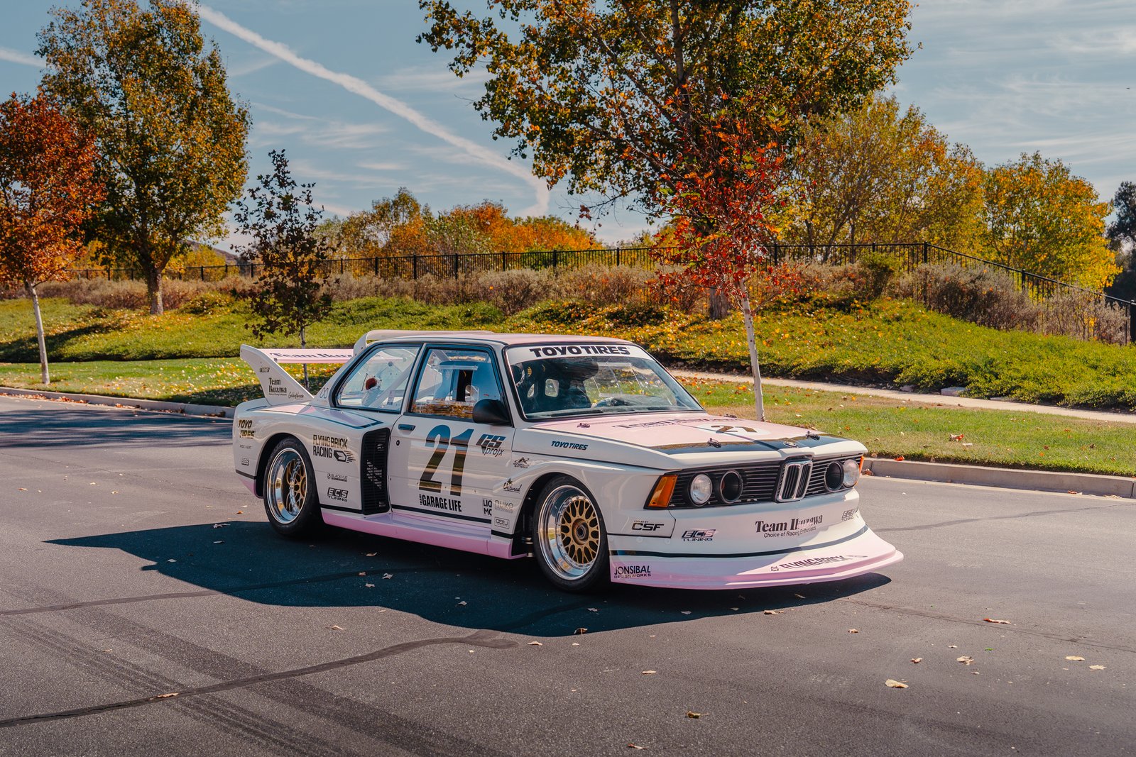 Pink and white Team Ikuzawa BMW E21 Group 5 front three-quarter in autumn setting