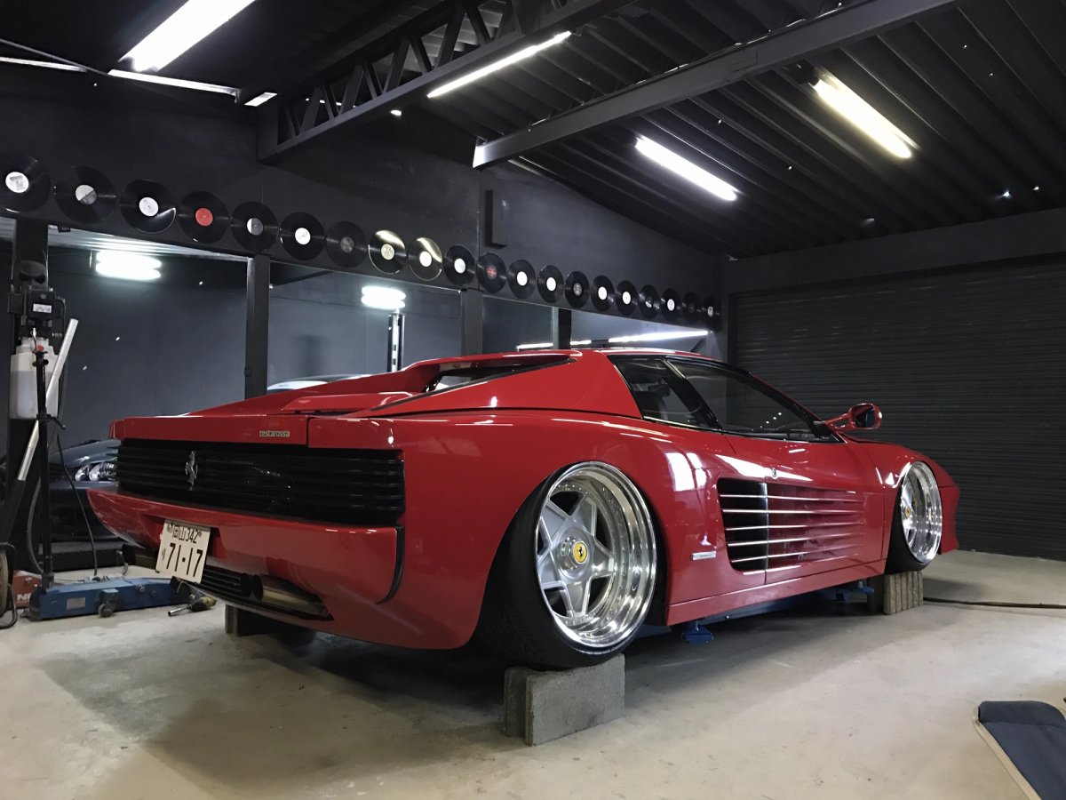 Ferrari Testarossa on jack stands inside Madlane workshop with vinyl records on the wall