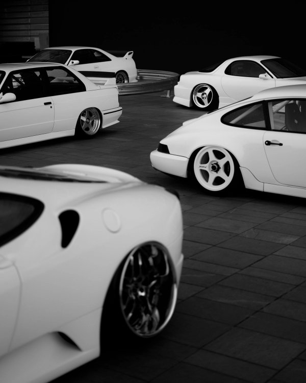 All-white curated lineup of stanced Porsche 964, BMW E30 M3 and other builds