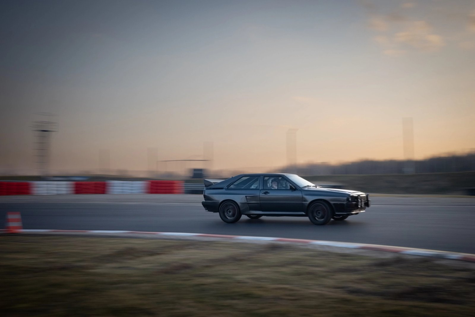 Panning shot of the Audi ur-quattro at speed on the track at dusk with motion-blurred background