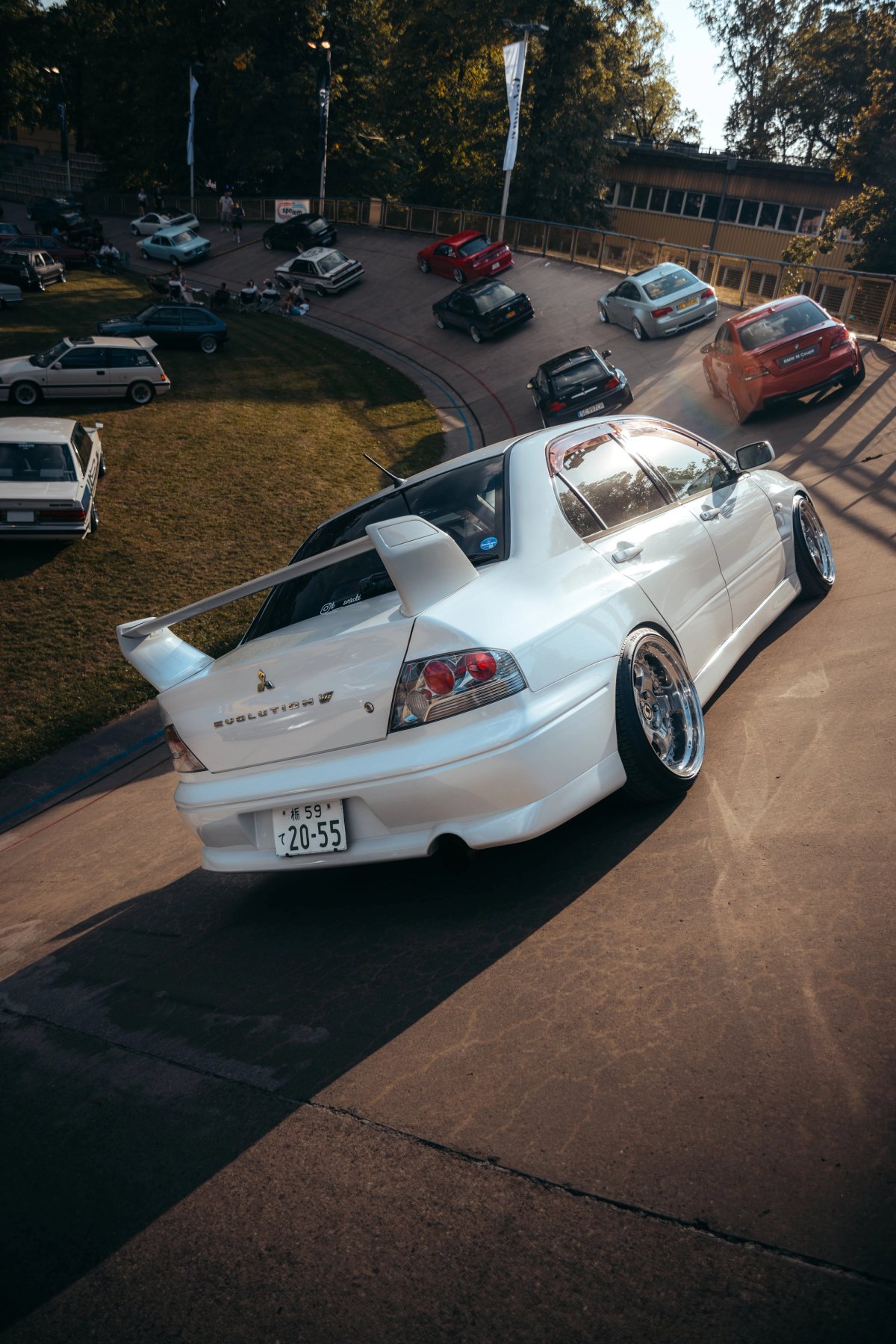 White Mitsubishi Lancer Evolution on the velodrome banking with Japanese plates at golden hour