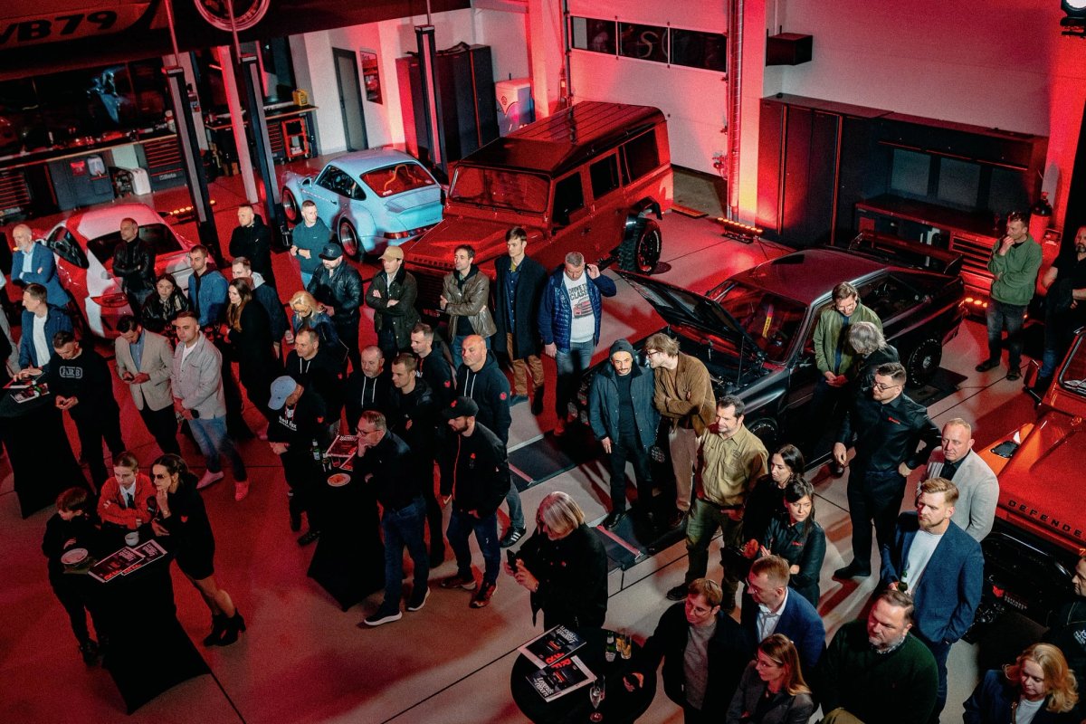 Overhead view of the Red Fox launch event crowd in the showroom surrounded by Defenders and supercars under red lights