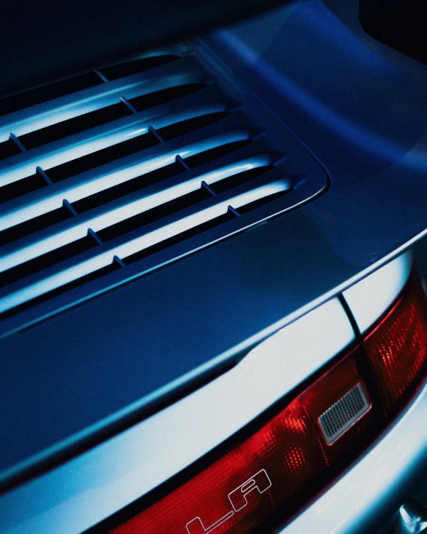 Detail of a classic Porsche 911 ducktail rear spoiler and tail light in blue moody lighting