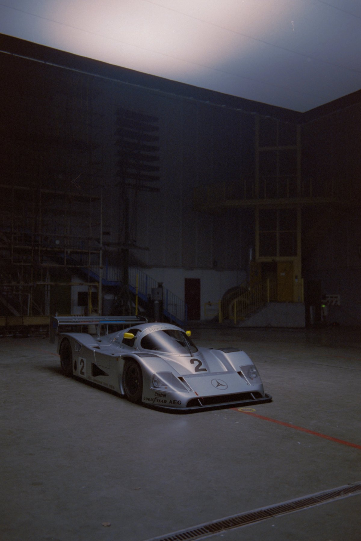 Mercedes Sauber C11 three-quarter front in the industrial space with warm light spill from above