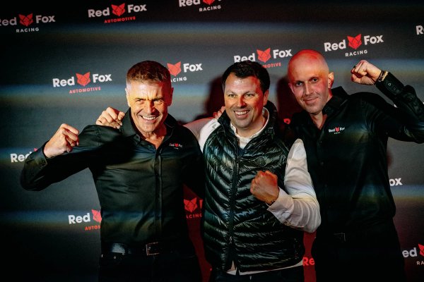 Three men posing in front of the Red Fox Automotive and Red Fox Racing backdrop, fists raised