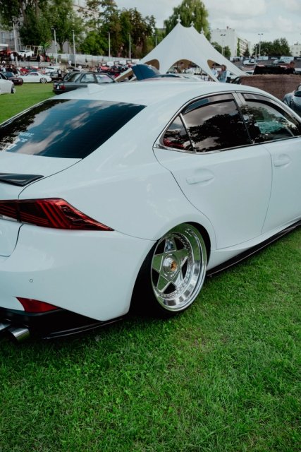 Rear three-quarter view of a white Lexus IS sitting low on polished deep-dish wheels