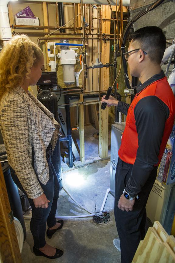 Adams Pest Control technician showing a homeowner a water intrusion issue in a basement, identifying pest risks in Minnesota homes