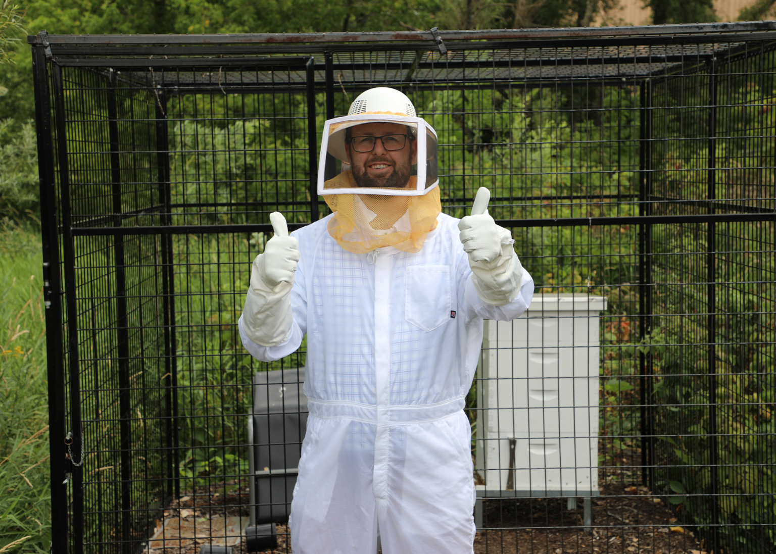 Professional beekeeper in protective suit giving thumbs up during safe bee removal by Adams Pest Control in Minnesota