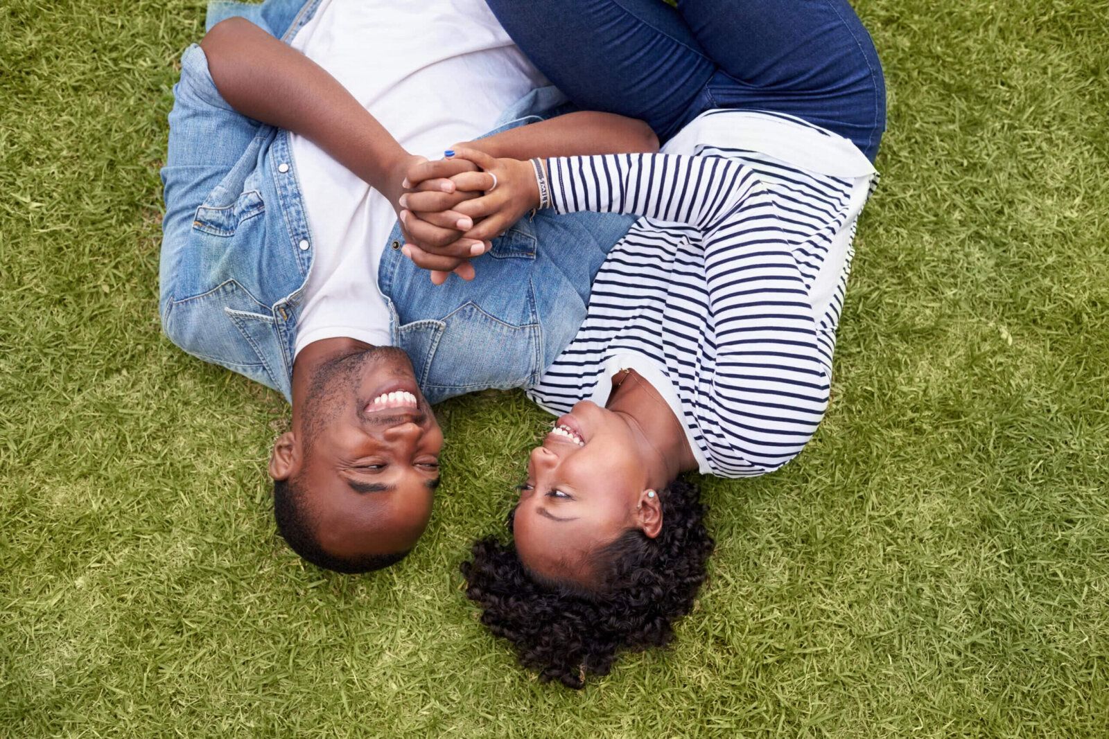 Happy African American couple lying on green grass in their backyard enjoying a pest-free outdoor space