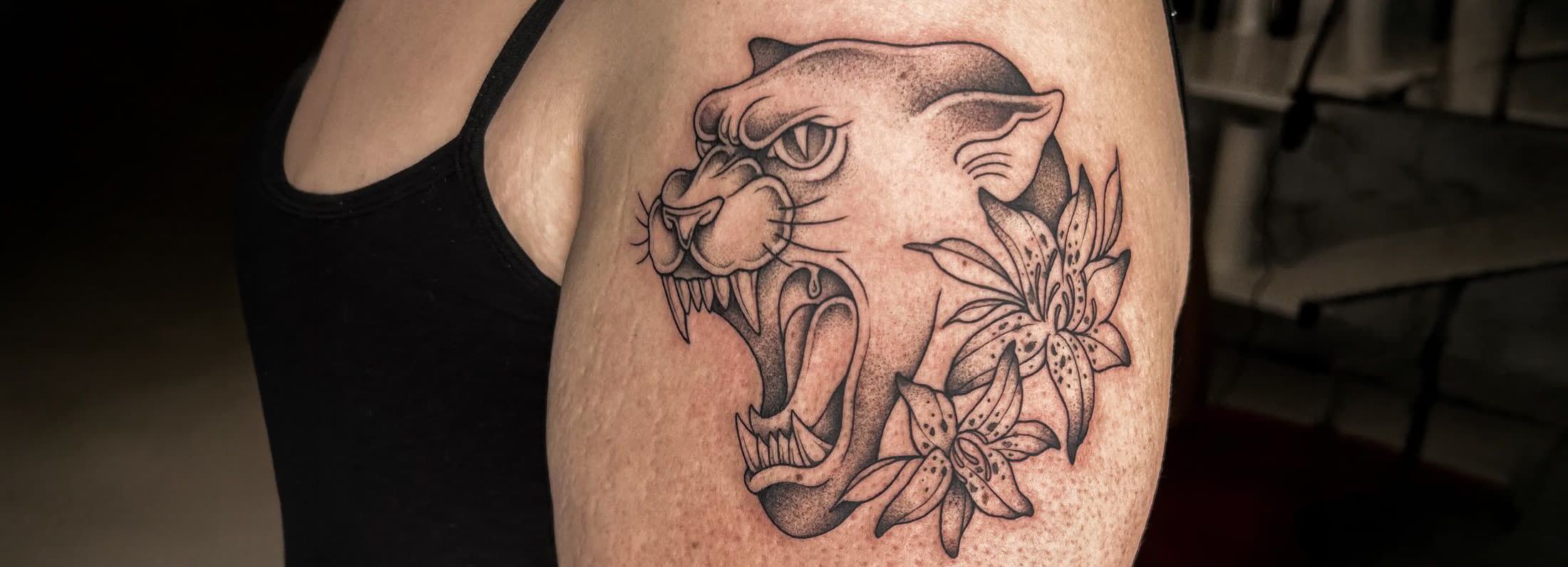 Fauchender Panther mit Lilien am Oberarm — Tattoo aus dem Studio in Hohenweiler, Vorarlberg