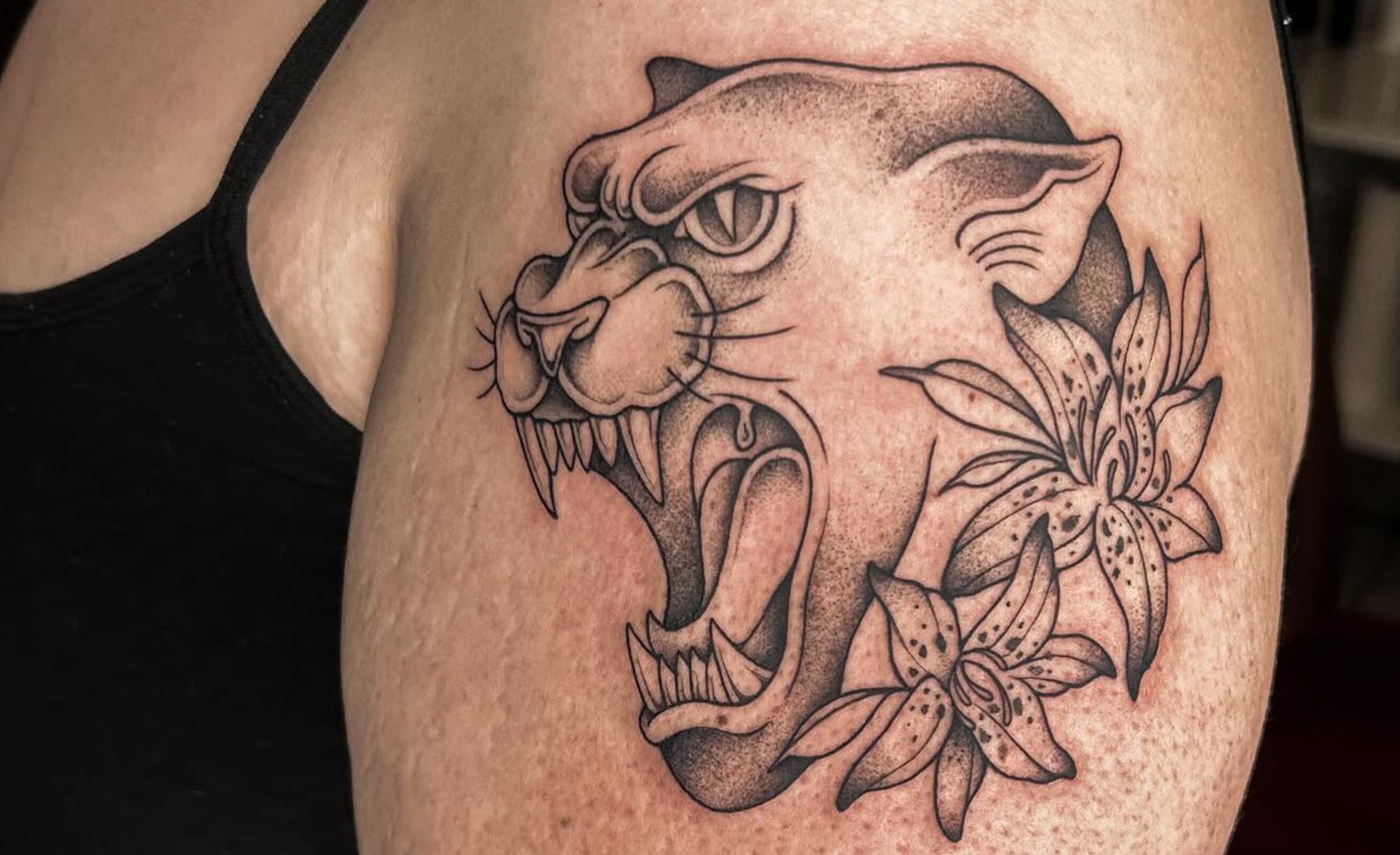 Fauchender Panther mit Lilien am Oberarm — Tattoo aus dem Studio in Hohenweiler, Vorarlberg