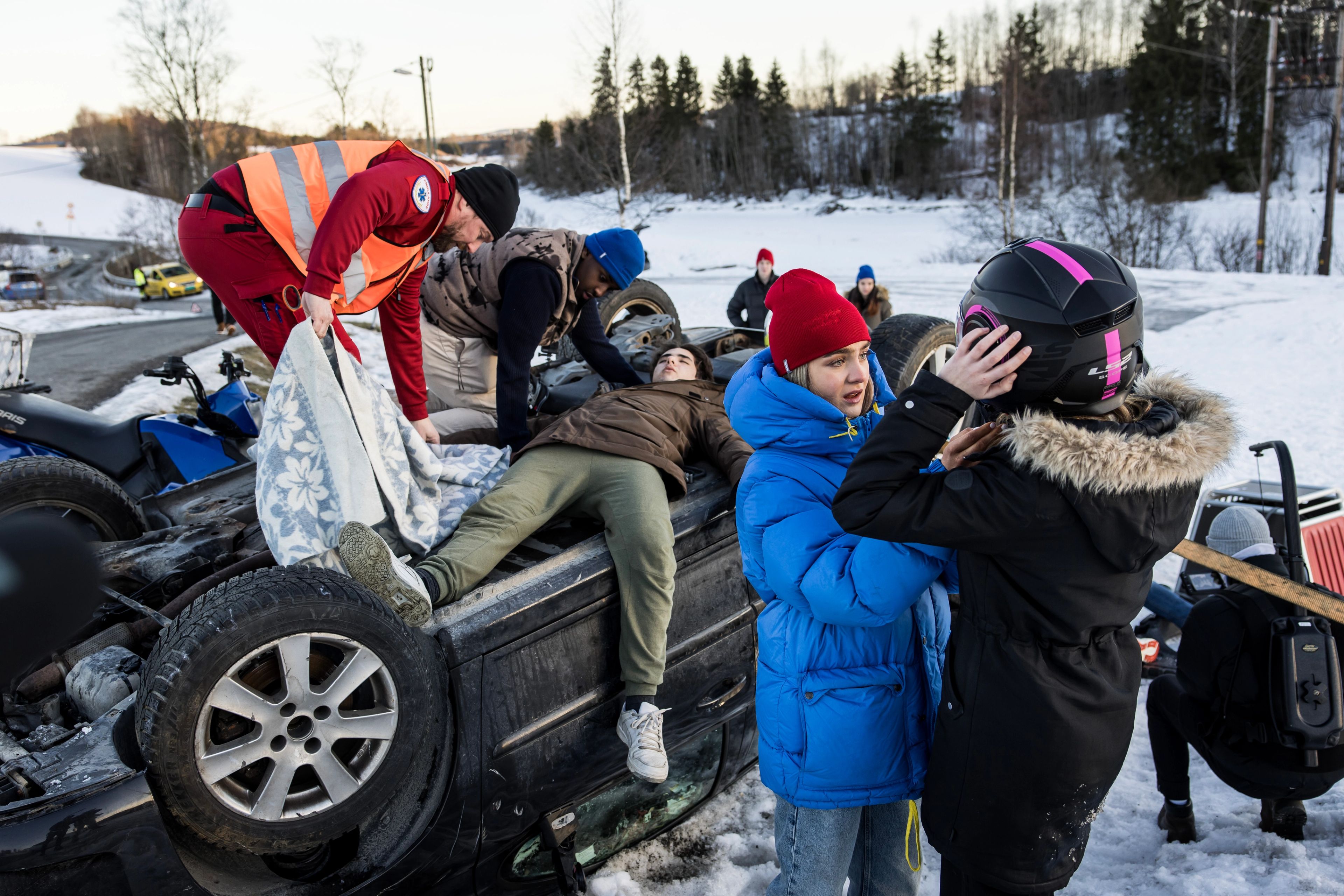 Ulykkessted med veltet bil og personer som hjelper skadde