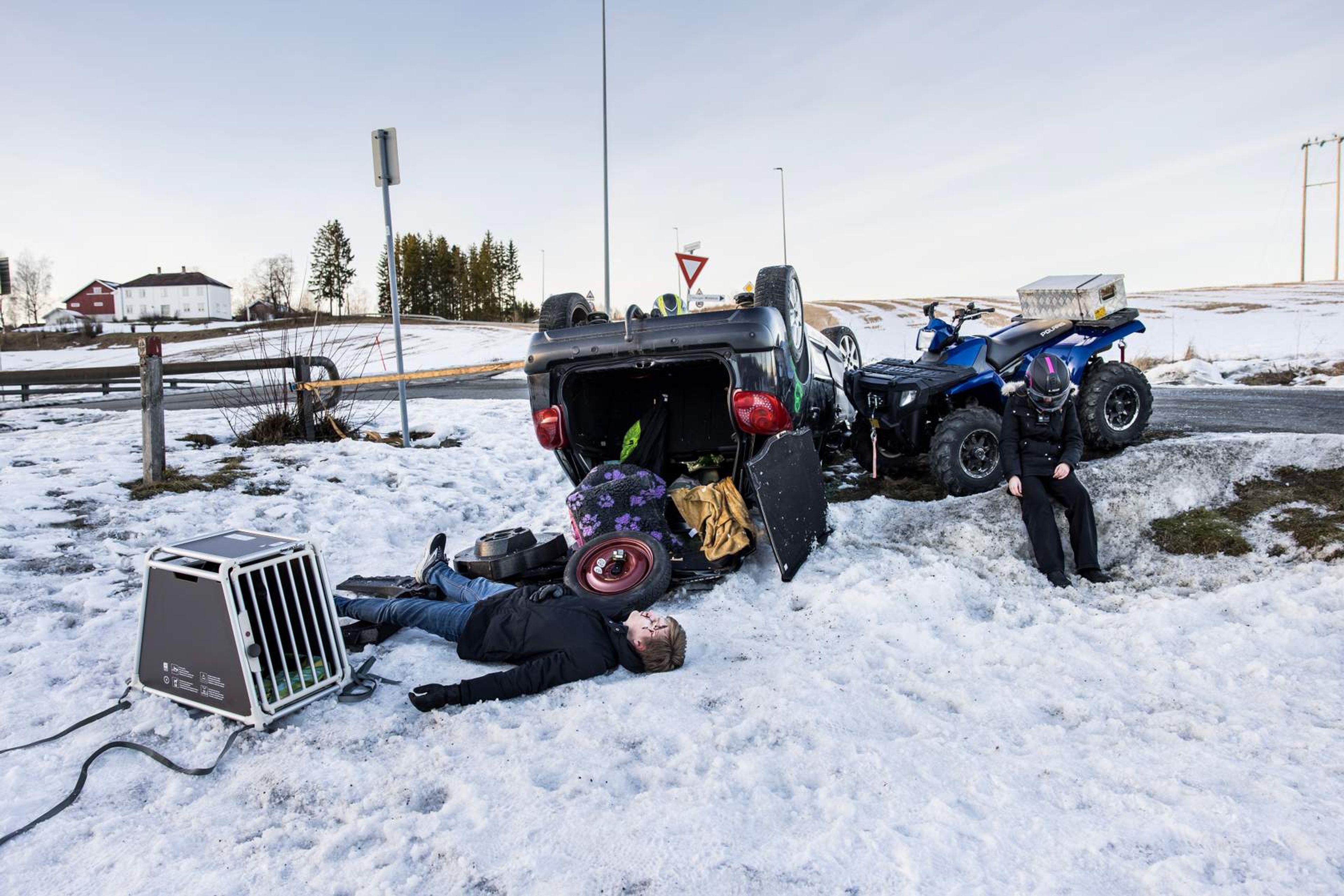 Ulykkessted med en bil som ligger på taket og to skadde personer