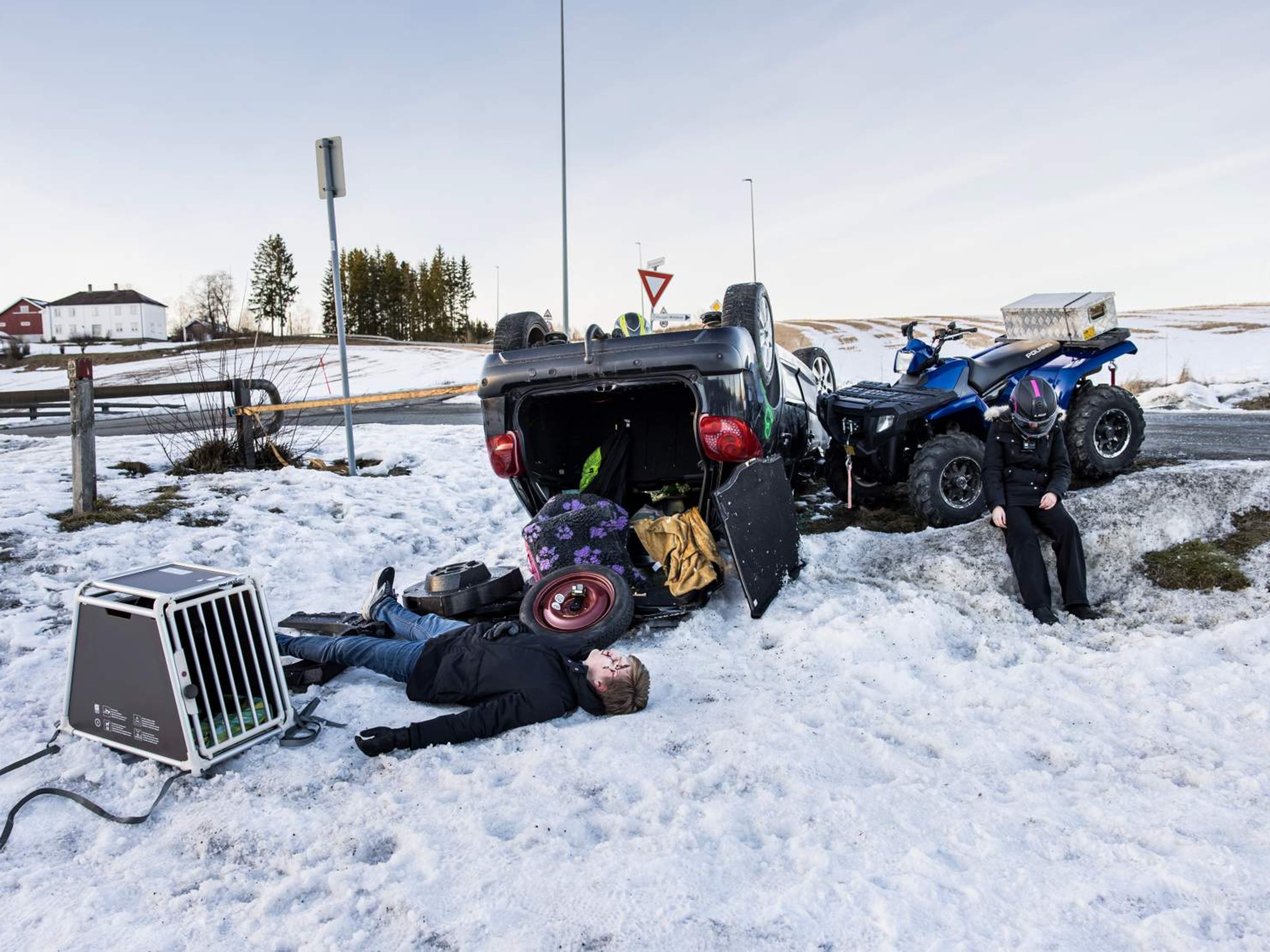 Iscenesatt ulykkessted av bil, og ATV, med et hundebur og to mennesker.