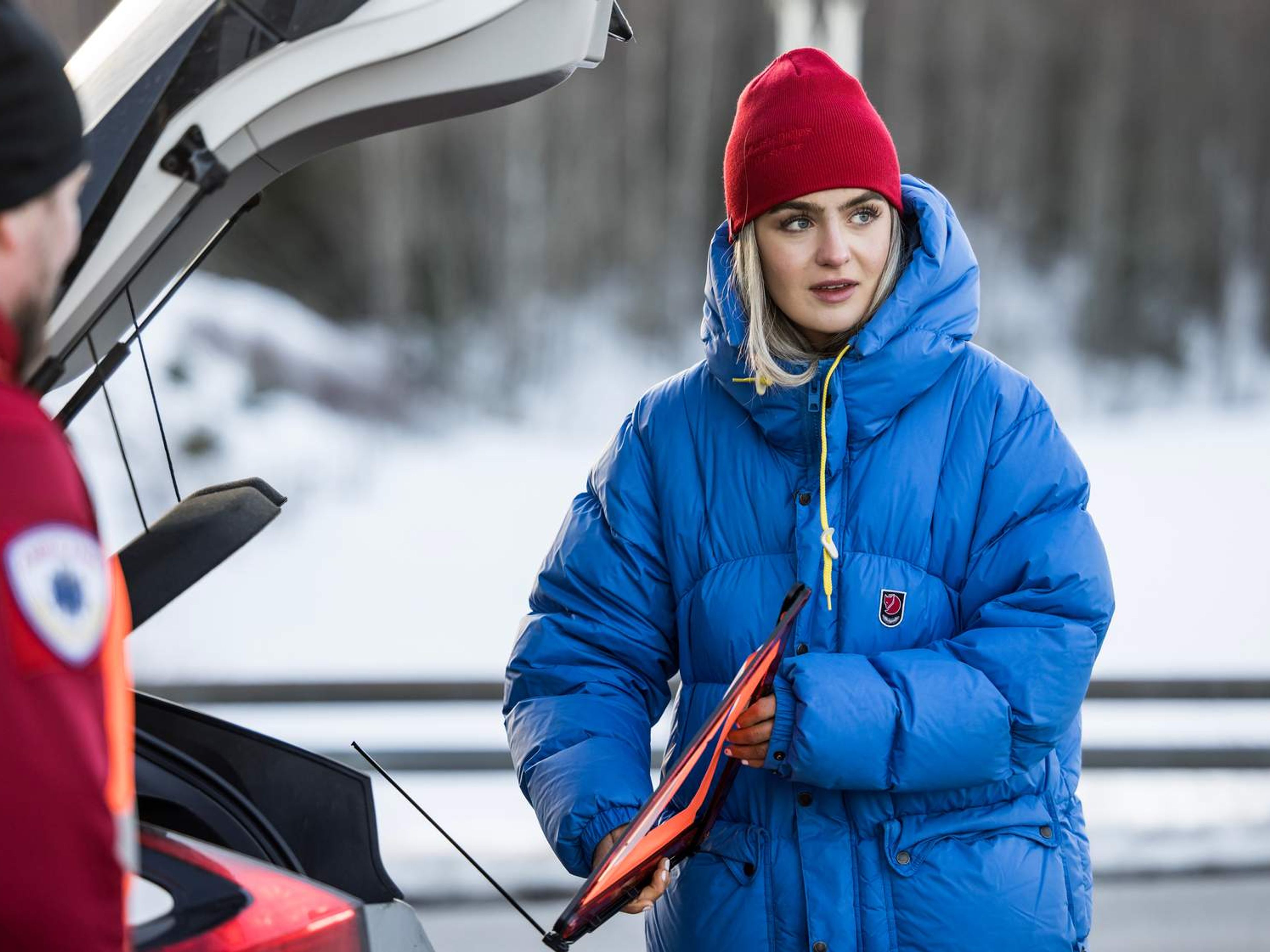 Ung kvinne tar ut en varseltrekant ut av bilen.