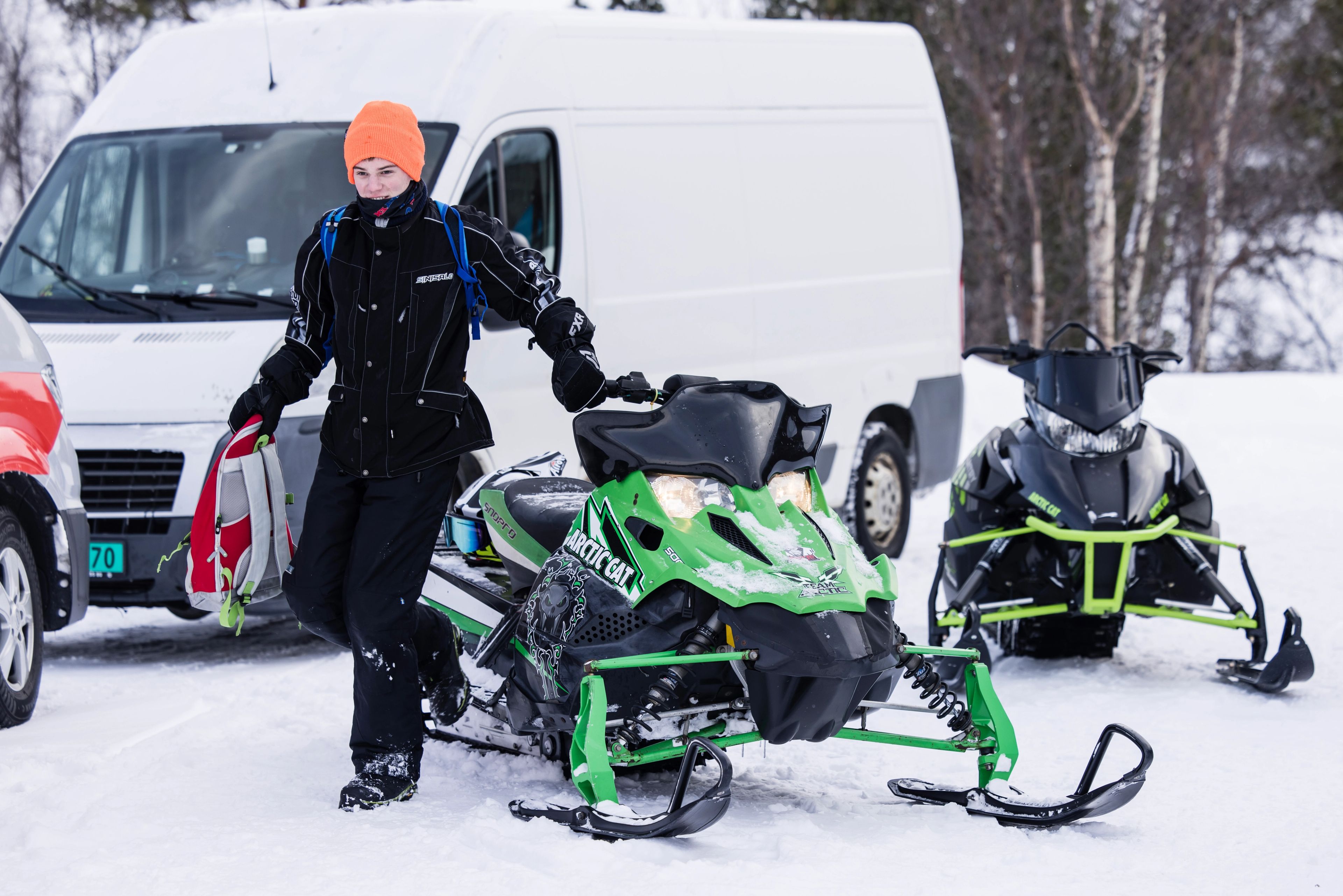 Person med en sekk i hånden som går bort fra en snøscooter