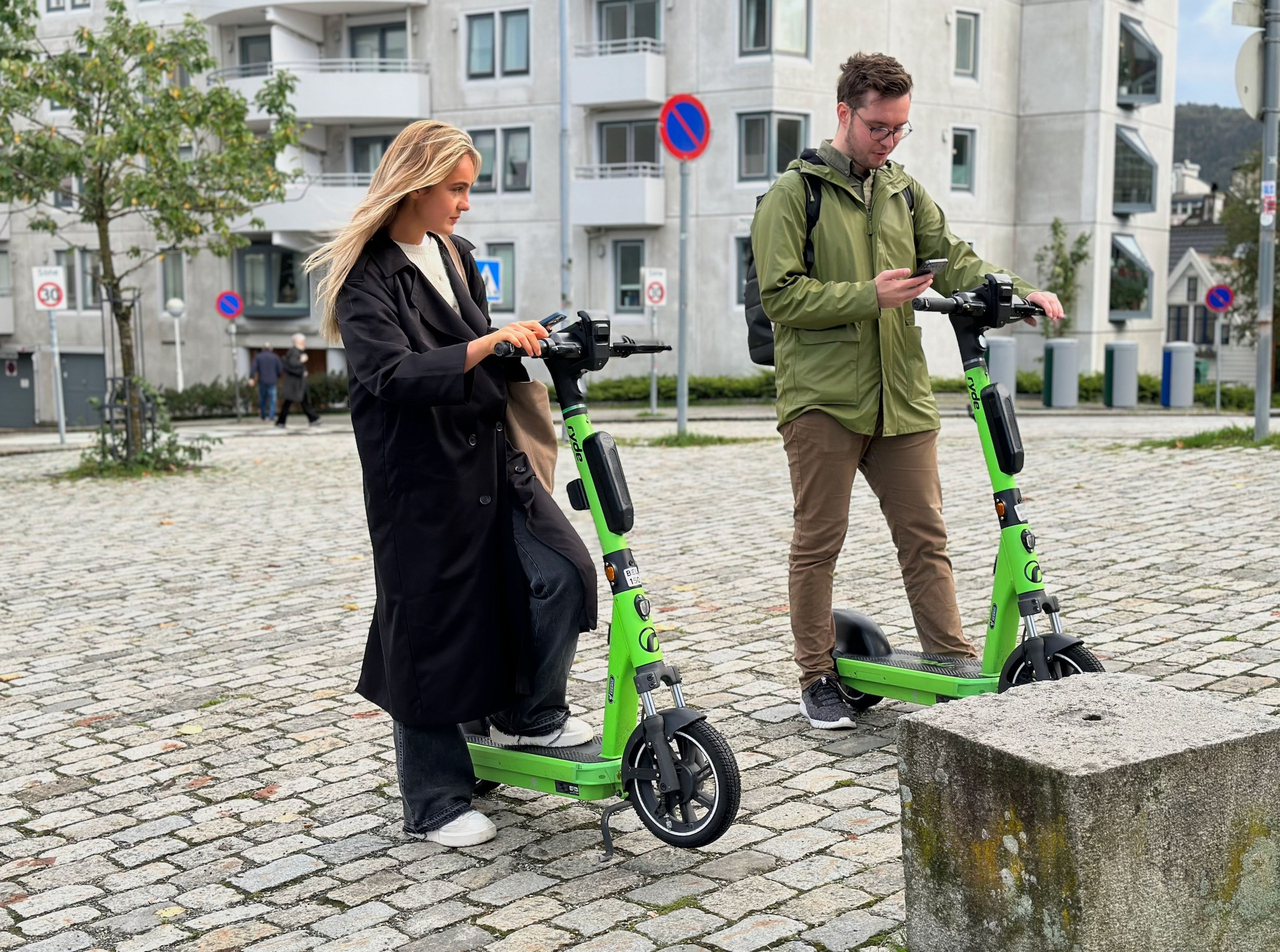 To personer som låser opp hver sin elsparkesykkel
