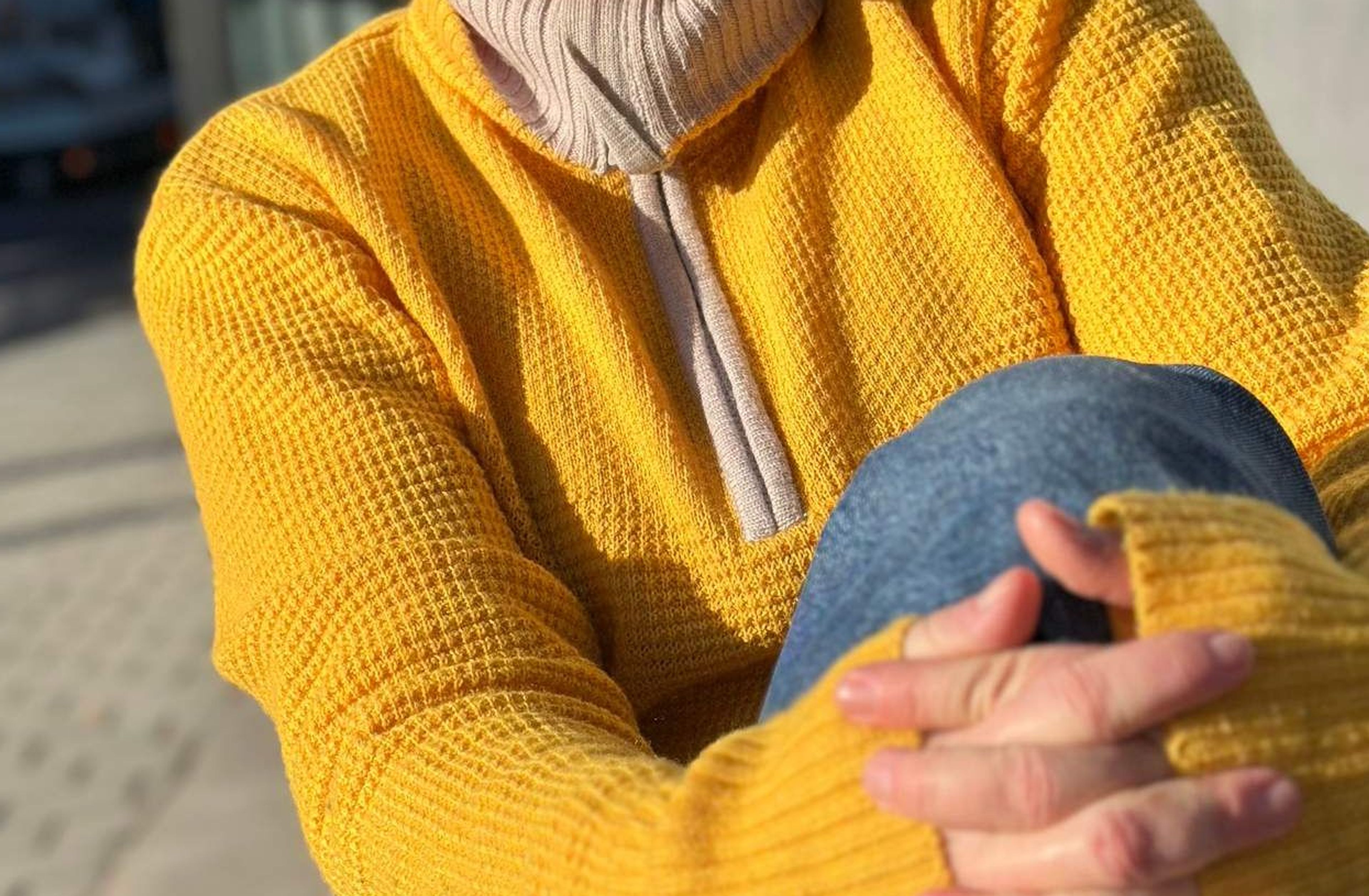Person som sitter med hendene foldet rundt det ene kneet