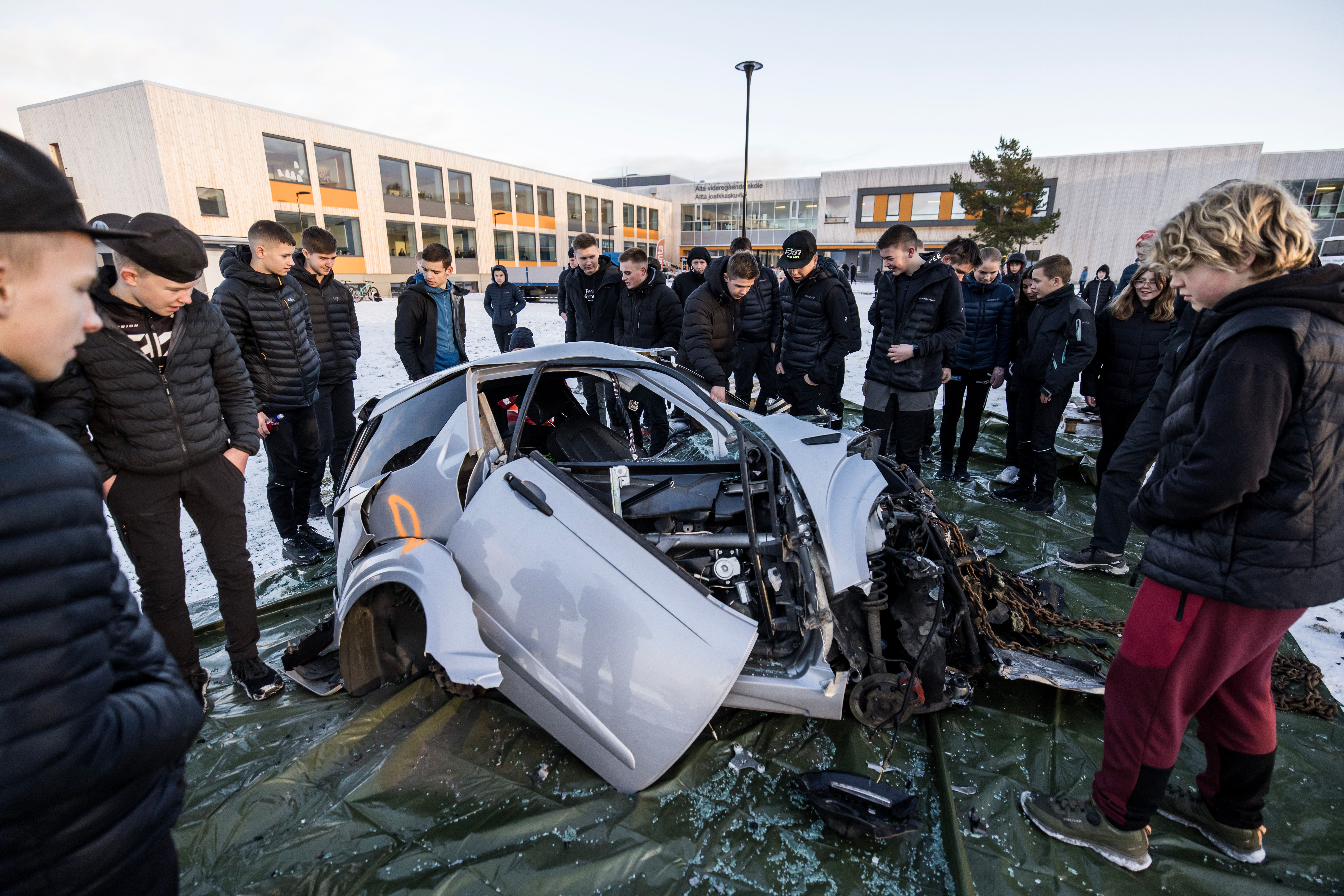 Elever som står i ring rundt en krasjet bil