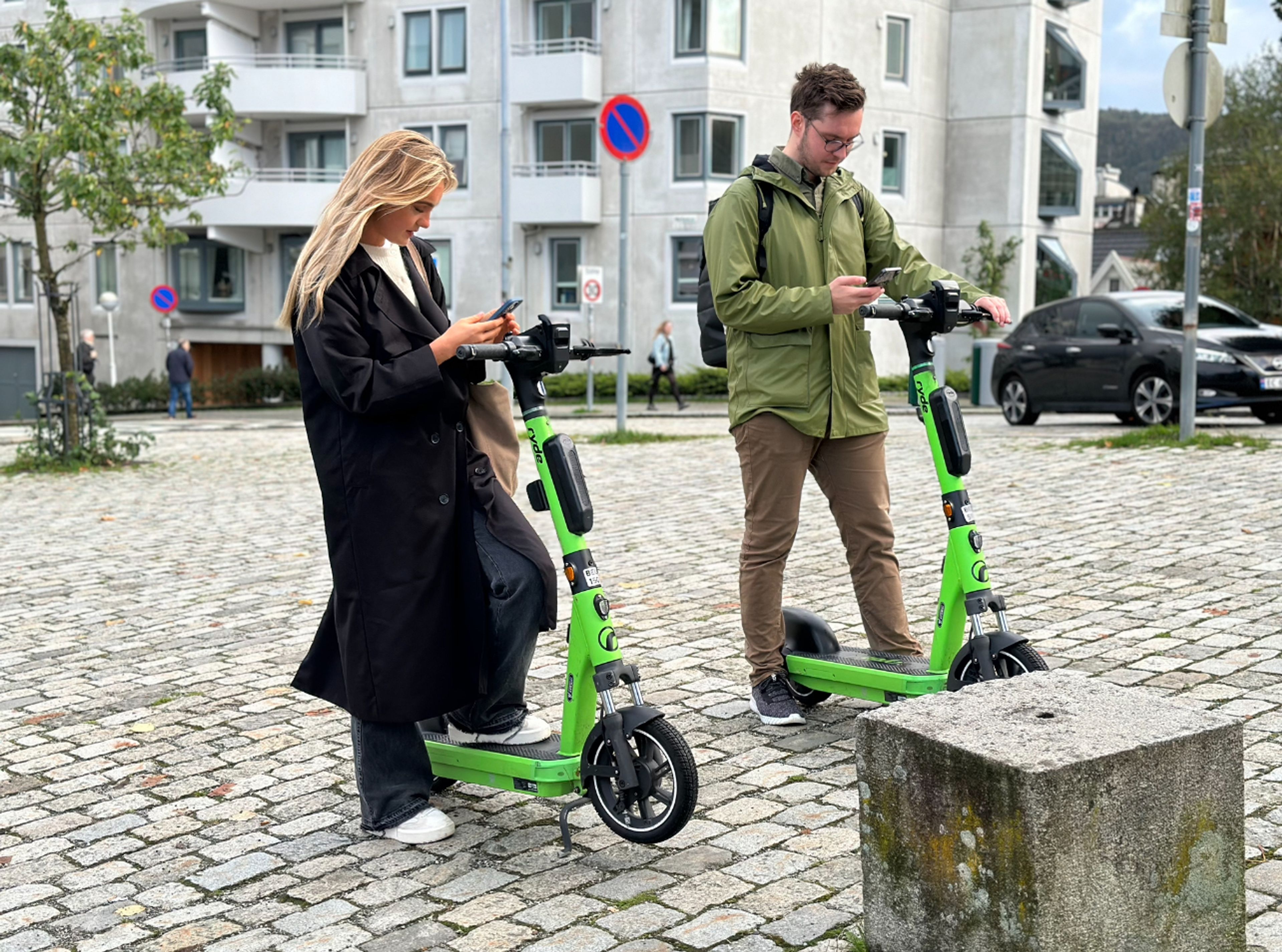 To personer på som låser opp hver sin elsparkesykkel