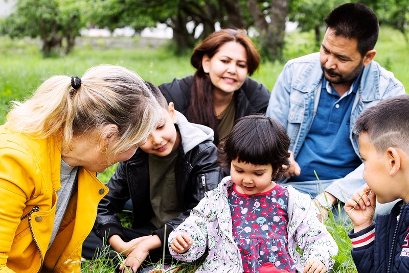 Familiekontakt sitter på gresset med familie.