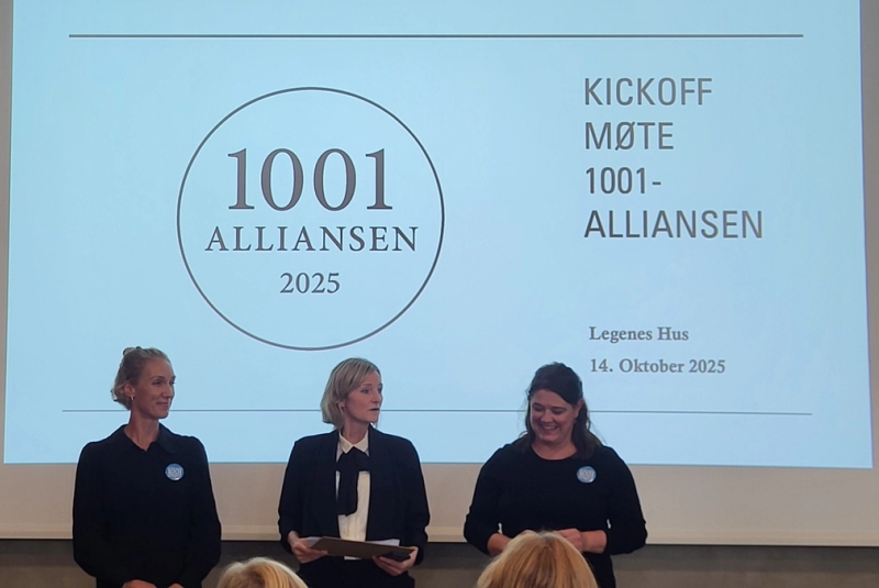 Bilde av tre personer på en scene foran en powerpointpresentasjon