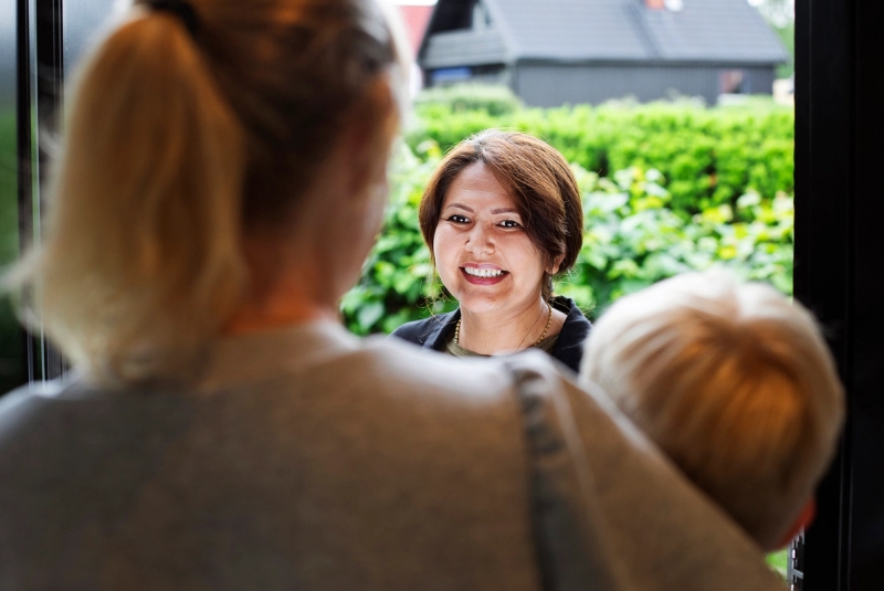 Familiekontakt i døra. Snakker med mor og sønn i døråpning.