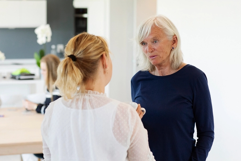 Familiekontakt og mor står og prater sammen, med 2 barn i bakgrunnen.