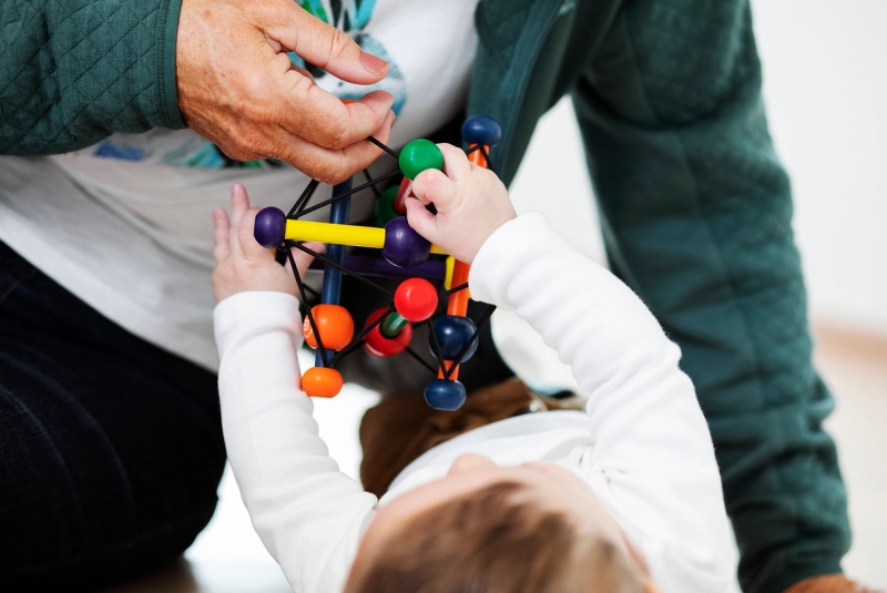 Familiekontakt leker på gulvet med liten baby.