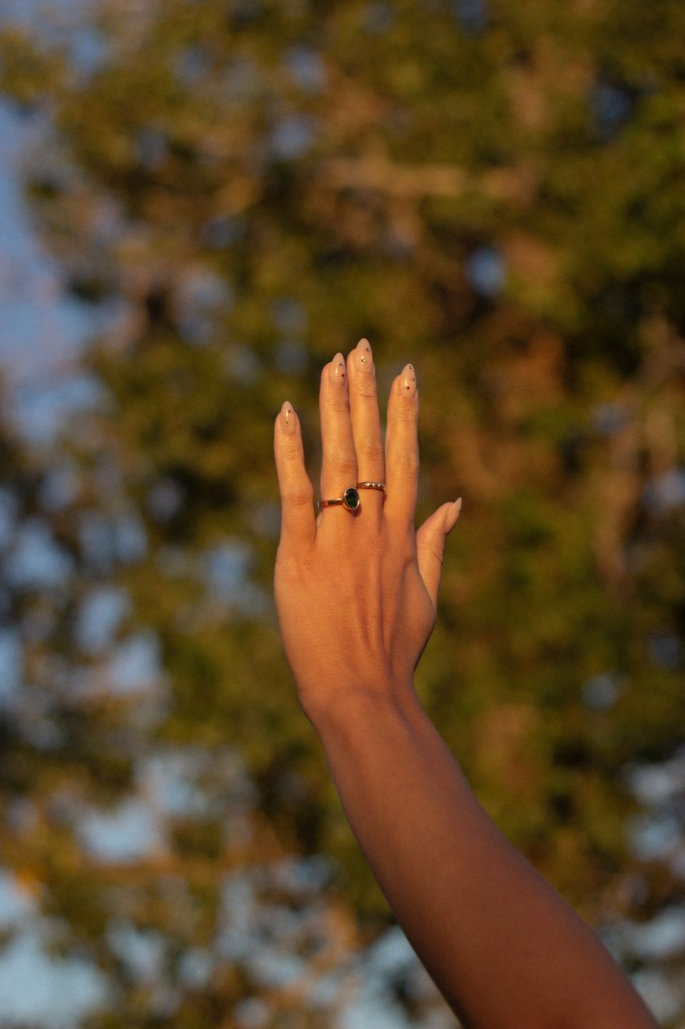 A raised hand wearing rings
