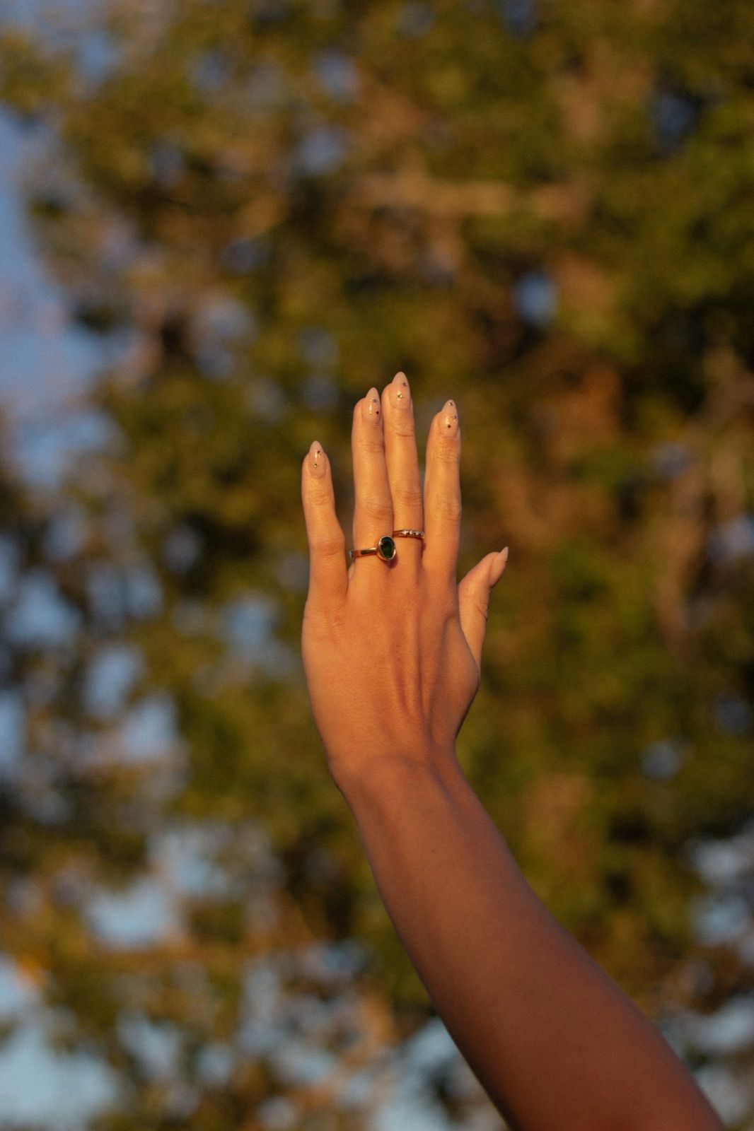 A raised hand wearing rings