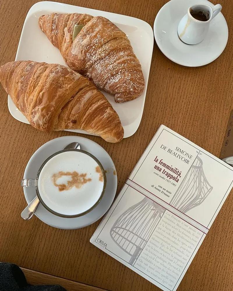 Libro di simone de beauvoir, cappuccino, cornetto, caffetteria