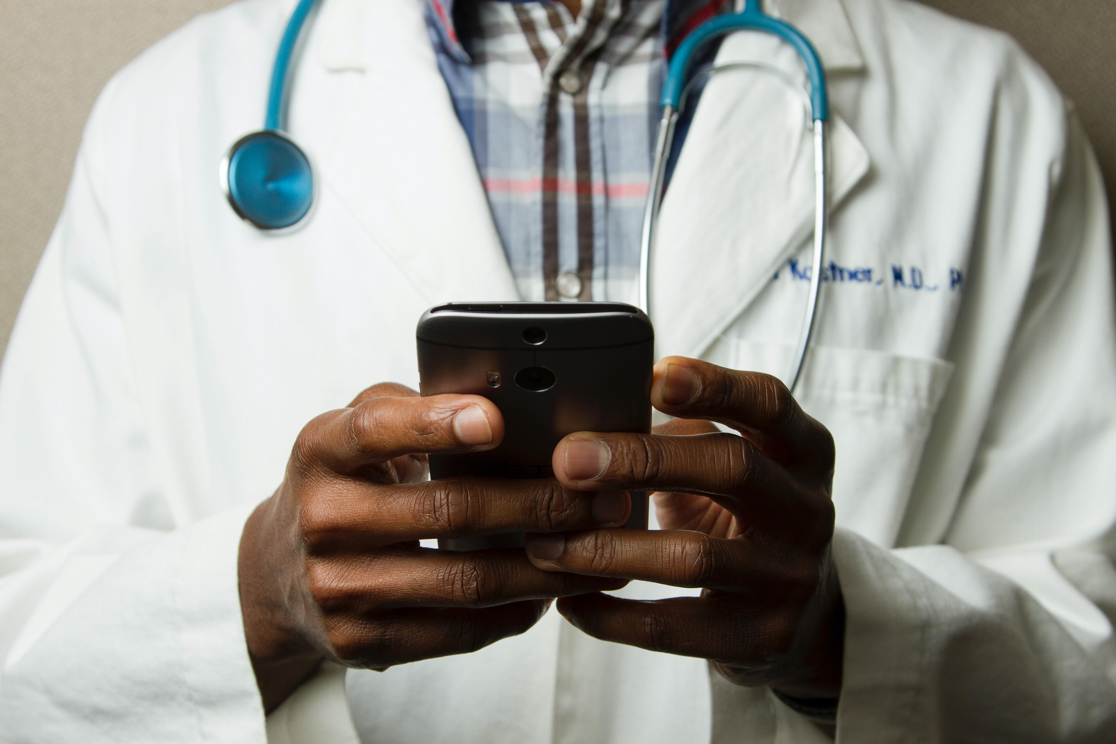 Doctor using a mobile phone to text some instructions