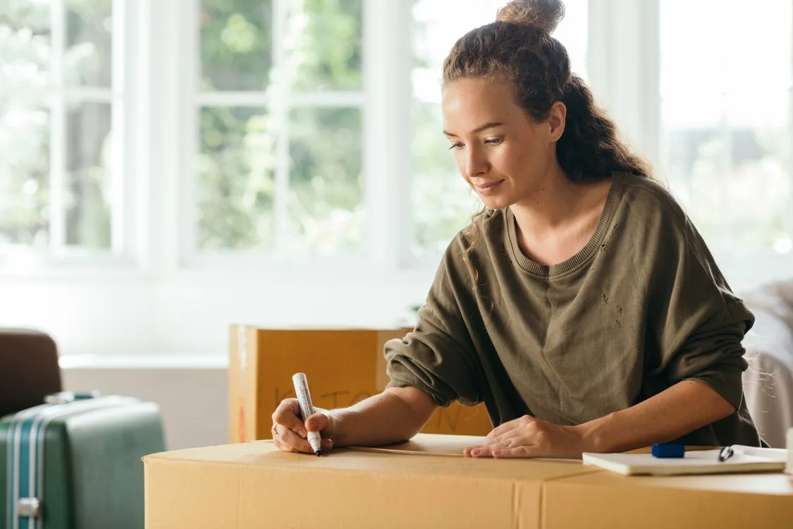 Vrouw schrijft een etiket op een verhuisdoos om haar spullen te ordenen