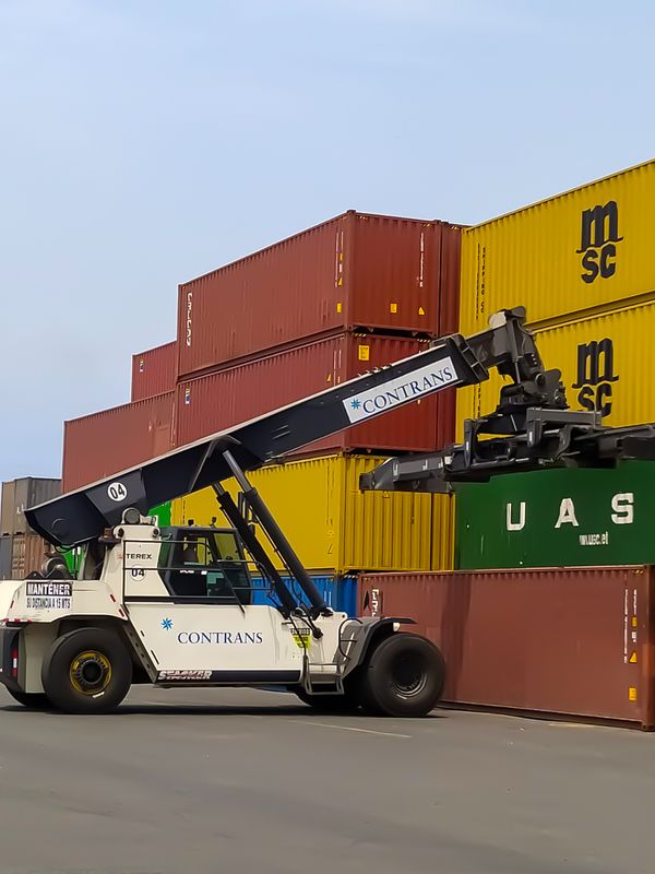 Operación de reach stacker o apilador retráctil en puerto marítimo.