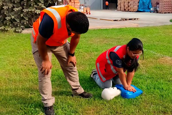Instructores de Consitec Perú realizando práctica de primeros auxilios y RCP durante una capacitación de seguridad y salud en el trabajo en instalaciones de empresa cliente.