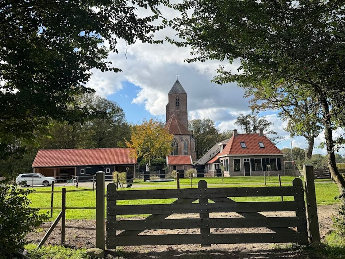 Een grote groep deelnemers zit in een kring onder een open tent