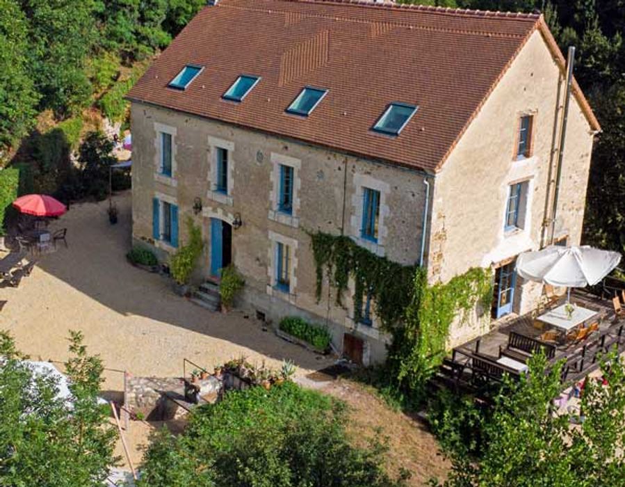 Le Moulin van bovenaf gezien, met terras en parasols tussen de bomen