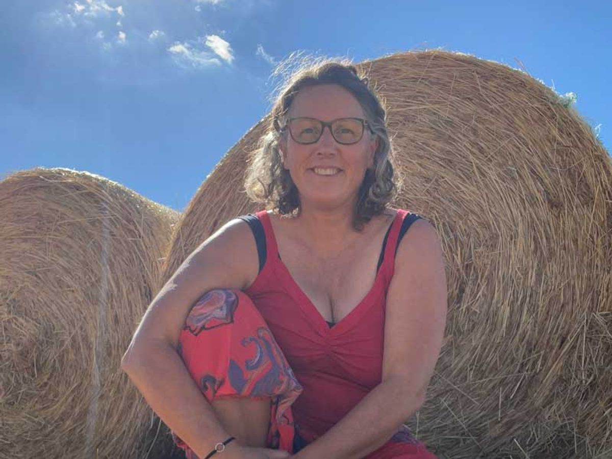 Judith van den Berkmortel lachend bij een strobaal onder een strakblauwe lucht