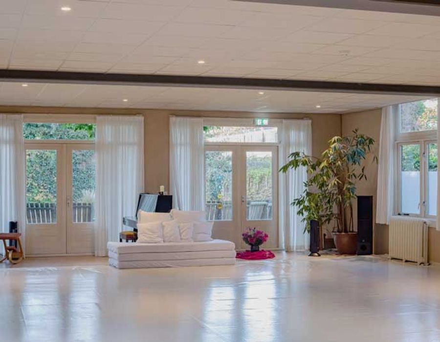 De lichte zaal van Cordium in Nijmegen, met hoge ramen en een witte bank